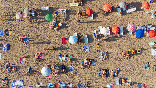 Aerial view of vibrant umbrellas and sunbathers dot the golden sands, creating a lively tapestry of summer leisure, Sremska Mitrovica, Vojvodina, Serbia.