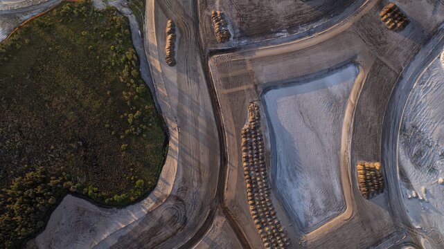 Aerial view of freshly cultivated earth contrasting with a verdant patch of trees, creating a textured landscape from above, West Palm Beach, Florida, United States.