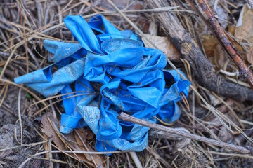 one old crumpled blue roll of plastic old blue electrical tape lies on the ground and gray dry grass outside