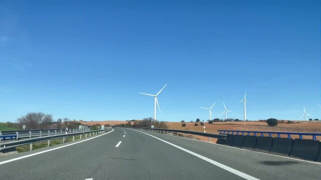 conduciendo y circulando en coche por carretera de autopista desde dentro con molinos e&oacute;licos de viento y cielo azul