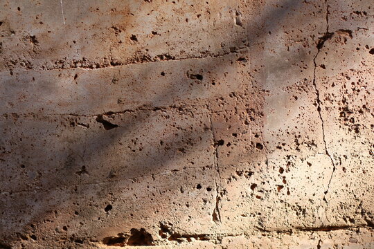 Textured rammed earth wall with natural light and shadows creating depth and contrast