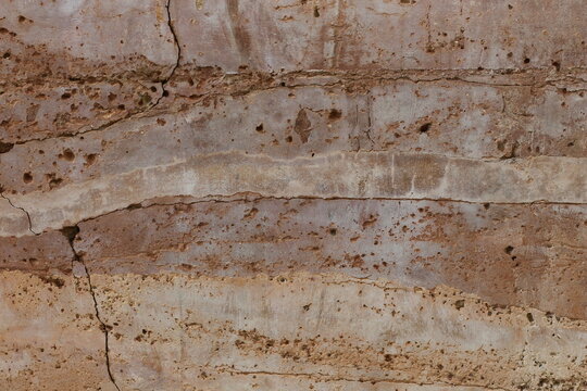 Close-up texture of layered rammed earth wall with visible cracks and imperfections