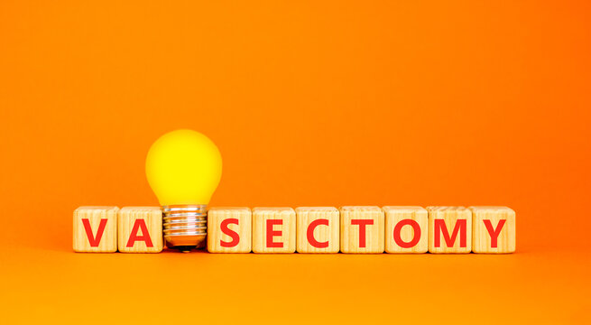 Vasectomy word symbol. Concept word Vasectomy on beautiful wooden blocks. Beautiful orange background. Beautiful yellow light bulb. Medical support vasectomy word concept. Copy space.
