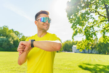 Runner checks watch while enjoying sunny weather in a park during late morning hours