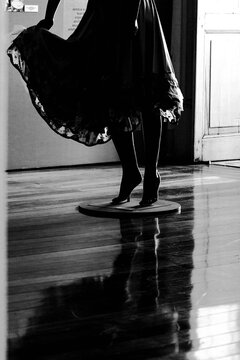 Pernas, p&eacute; e vestido em manequim sobre piso de madeira em sala iluminada pela luz solar.  