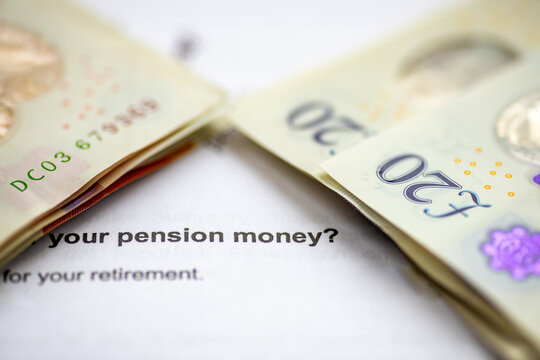 A macro close up of stacks of Pound Sterling bank notes on top of a pension planning letter.
