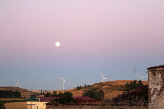 Sunrise over dirt path and windmill and full moon in Rabe de las Calzadas July 2024