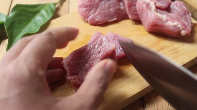 slicing raw beef on a chopping board