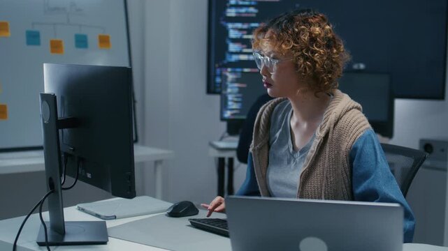 Software Engineer, AI Programmer Software Developing, Focused Female Computer Programmer working on Computer Writing Code, Developing software application looking at Screen in Tech Office at night.