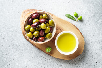 Olives in wooden bowl and fresh olive tree branch at white background.