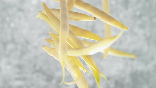 Yellow Beans Falling Into Pot Of Boiling Water Making A Splash In Slow Motion, Table Top View