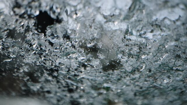 detail - removing ice from a car window in winter - slow motion macro shot
