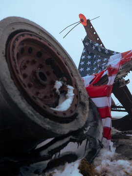 Wreckage at the B-29 crash site on Bleaklow moor in the Peak District National Park, England, with an American flag and poppy placed as a memorial tribute. Winter conditions with snow and rusted metal