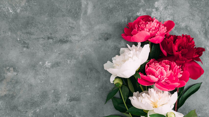 Top view of red and white peony flowers bouquet on grey stone background. Floral composition with copy space for text. Elegant flat lay for wedding, Mother's Day, or romantic greeting card. © prime1001