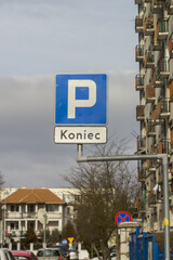 Znak „koniec parkingu” pod niebieskim symbolem P na ulicy przy blokach mieszkalnych – organizacja ruchu i infrastruktura miejska. © Henryk Guziak