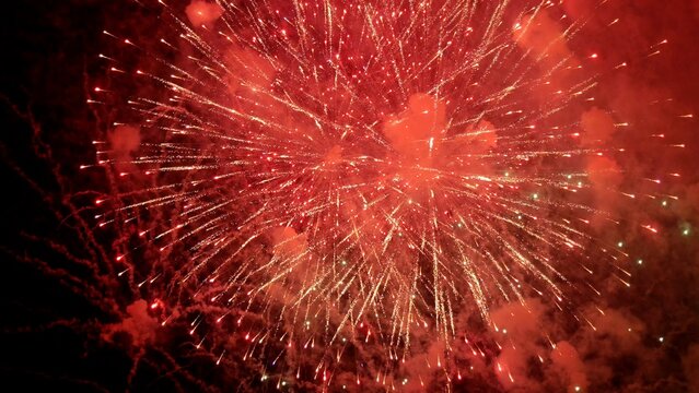 scarlet fireworks brighten midnight sky scene, dynamic crimson pyrotechnics illuminate evening with smoky radiance, lively night explosion of red fireworks casting glowing halos across darkened sky