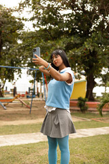 Smiling Young woman having a video call on smartphone outdoors in a park