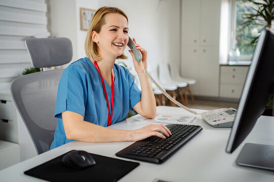 Healthcare professional smiling talking on telephone working at clinic