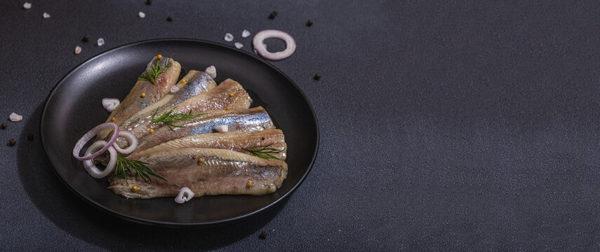Fillet of pickled marinated sea herring fish with shallots and dill. Served ready to eat seafood
