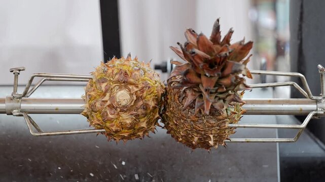 Grilled pineapples with smoky aroma, Freshly cooked pineapples turning golden under flavorful smoke, Vibrant street market scene with pineapples cooking on rotating spit