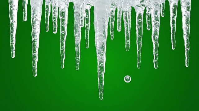 A row of sharp, clear icicles hanging against a vibrant green background, with a single water droplet falling from one of the ice formations, creating a dynamic winter scene.