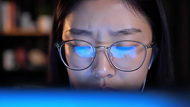 Young Asian woman working on computer with digital map reflection in glasses