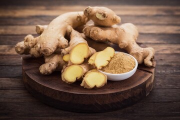Fototapeta premium Fresh Ginger Roots and Ground Spice on Rustic Wooden Surface.