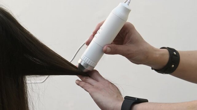 Trichologist examines hair and scalp of young woman in salon using trichoscope and dermatoscope. Hair loss, split ends problems, scalp treatment and hair care consultations Closeup hands no face