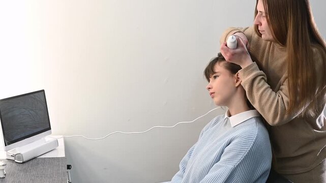 Trichologist examining scalp with digital dermatoscope, close up of hair and skin analysis on screen. Woman specialist performing hair diagnostics procedure in modern clinic, medical consultation conc