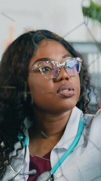 Close up of pleasant professional adult multiracial male and female medical colleagues in white gowns which standing together in front of glass wall and investigating x-ray image