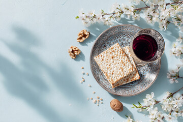 Passover with matzo, red wine and spring blossoms on blue background. Flat lay, copy space
