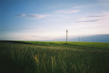 Obraz premium Minimalist landscape with power lines in a grassy field, analog photography