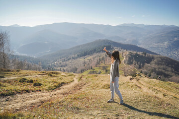 Obraz premium Woman pointing toward mountains on scenic trail