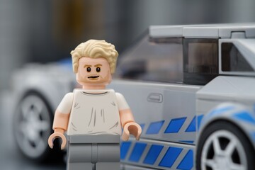 Fototapeta premium Tambov, Russian Federation - August 21, 2025 Portrait of a Lego Brian OConner minifigure near his Nissan Skyline GT-R (R34) car. 2 Fast 2 Furious movie. Lego Speed Champions