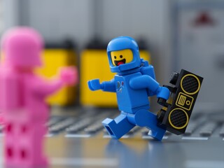 Fototapeta premium Tambov, Russian Federation - May 30, 2025 A cheerful blue Lego astronaut minifigure running with a boombox towards a pink companion.