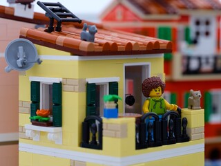 Fototapeta premium Tambov, Russian Federation - January 05, 2026 Lego woman minifigure standing on her balcony with cats. LEGO Ideas Italian Riviera set.