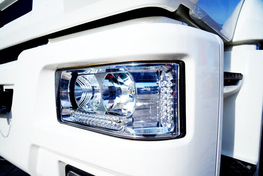 Headlight of truck close up. Close view of white truck headlight showing details of design and light features. LED headlamp, Truck headlight close-up. Bi-Xenon headlamps LED automotive lighting.