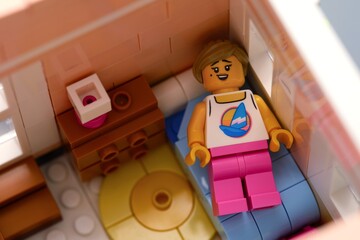 Fototapeta premium Tambov, Russian Federation - February 11, 2026 Lego woman minifigure lying on a blue bed in a miniature bedroom.