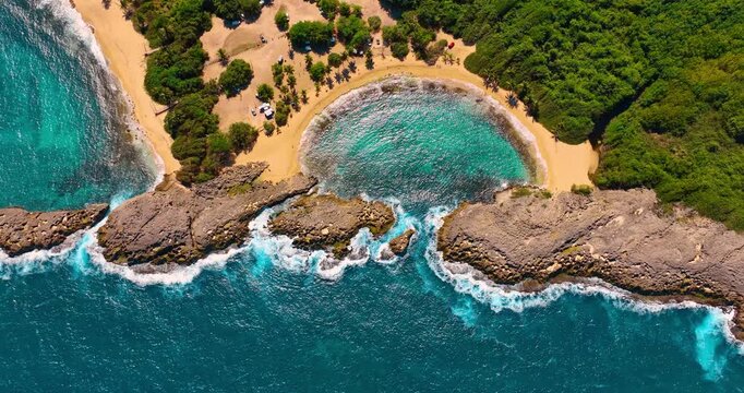 Foamy waves hit the rocks protecting sandy beach. Beautiful shore of Puerto Rico in Manati Beach. Top view.