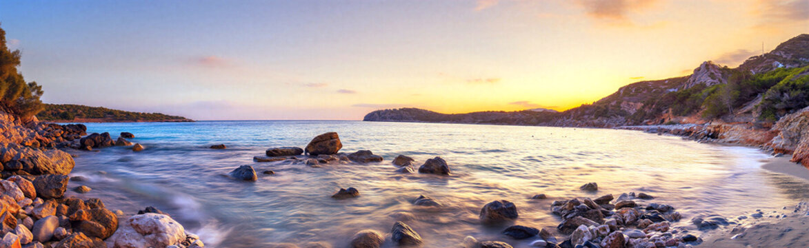 Panoramic sunset over a rocky beach with calm ocean waves