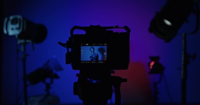 The operator turns on the camera and adjusts the lighting in the photo studio with lighting equipment. A mannequin is displayed on the camera screen. Backstage photo shoot .