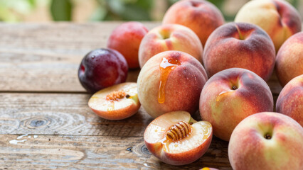 Obraz premium Ripe peaches, some halved to reveal juicy interiors, sit on a weathered wooden surface. Vibrant colors and a shallow depth of field create a fresh, appetizing scene.