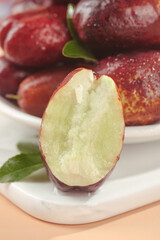 Fresh jujube fruits still life showcase with cut half revealing translucent flesh on white plate studio photography