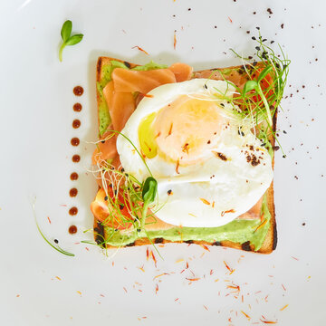 Premium avocado toast topped with a poached egg, smoked salmon, and fresh sprouts