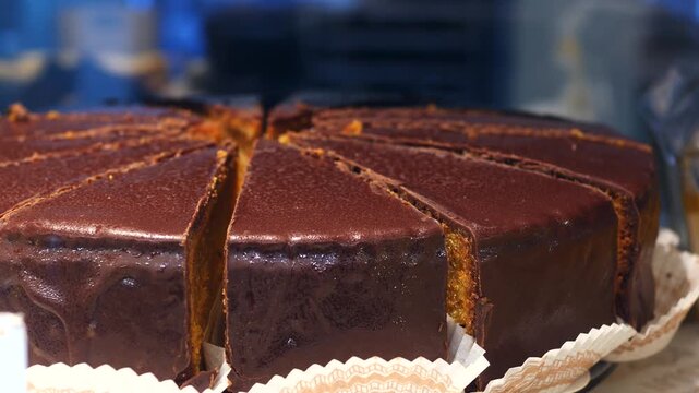 Delicious sachertorte, a traditional austrian chocolate cake with apricot jam, is sliced and ready to be served in a viennese pastry shop, showcasing the rich, glossy glaze and tempting layers