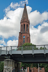Fototapeta premium Emmauskirche Neo Gothic Tower Peeking Over Gritty Urban Bridge Railing, Berlin - Germany