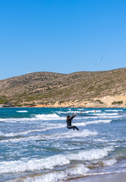 Kitesurfer riding waves in the sea with hills in the background at Prasonisi, Rhodes