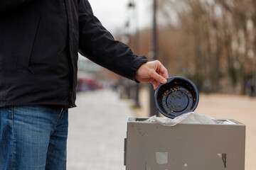 Naklejka premium Un homme jette un emballage plastique dans une poubelle en ville