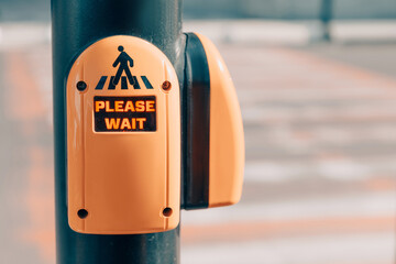 Pedestrian pressing button on traffic signal pole, waiting for walk sign at urban street crossing. Promoting road safety
