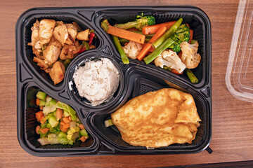 Packed bento box featuring chicken, omelet, mixed vegetables, and salad, ideal for a balanced diet and portion control
